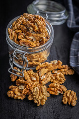 Peeled walnut kernels in jar on black table.