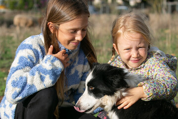Two kids are cuddling their dog 