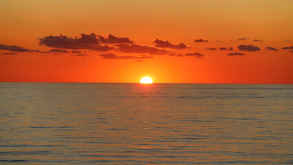 Orange sun rising on the horizon of calm sea