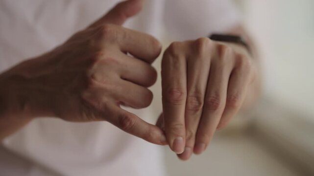 Man feeling anxiety and stress, biting nails, fidgeting fingers, coping with nervousness, unhealthy habit. Close-up of male hands showing tension and discomfort. Shooting in slow motion.