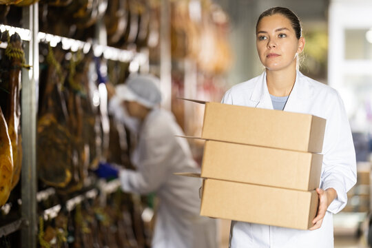 Female worker carries cardboard boxes of jamon at a factory