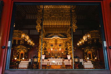 Obraz premium A gold altar glows within a Nara temple, viewed through red pillars. Chandeliers, canopies, and lanterns frame the central shrine in soft daylight, formal and reverent.