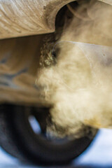 Close-up of car smoking exhaust pipe, car with gasoline engine. Gasoline engine warming up at idle in winter season. Blue exhaust smoke