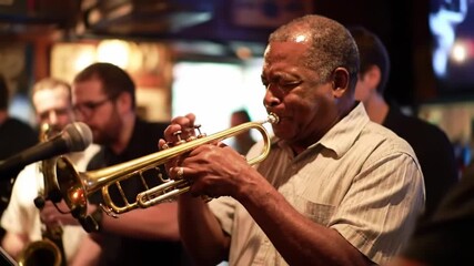 Man playing trumpet with band in a bar; live music entertainment concept