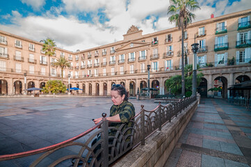 Naklejka premium Woman looking at phone in Plaza Nueva Bilbao