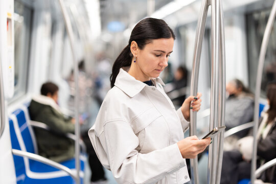 Portrait of woman using smartphone while traveling in subway car