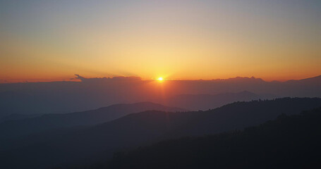 Stunning mountain vista at sunset with birds soaring through golden light and soft clouds creates a peaceful, inspiring atmosphere for travel and adventure