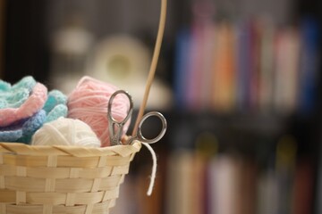 Basket with clews balls wool yarn and crocheted flowers handmade in the living room. blanket,  shelves books clock photo cozy home handmade 
