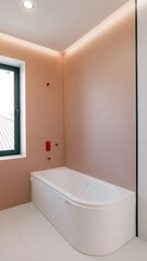 Modern bathroom interior with a white bathtub and pink walls