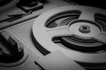 A close-up black and white photograph of an old tape recorder and a player for vinyl records and reel-to-reel tapes