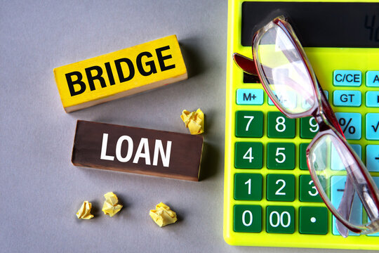 BRIDGE LOAN - words on wooden blocks with calculator and glasses in the background