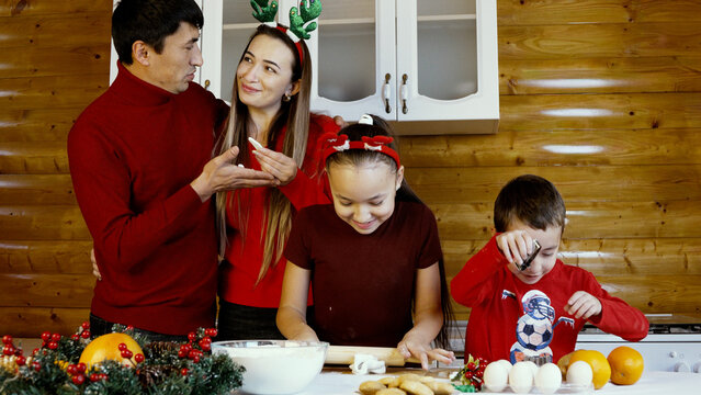 A family is baking Christmas cookies together in the kitchen - Powered by Adobe