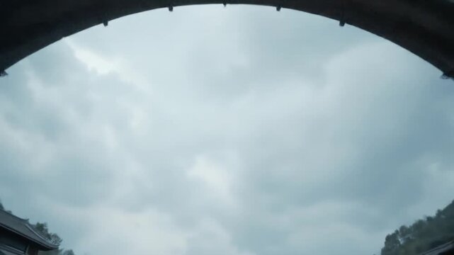 An ancient city gate with a layered roof and red lanterns stands tall in Enshi, China under a cloudy sky, showcasing traditional architecture. 4k video