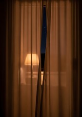 Warm Light Emitting Through Curtains on Nighttime Window Scene