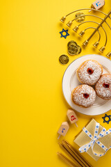 Vibrant vertical Hanukkah display featuring pastries, dreidel, menorah, coins, and a gift box on a sunny yellow backdrop. Warmth, tradition, and festive symbols convey holiday celebration and cheer
