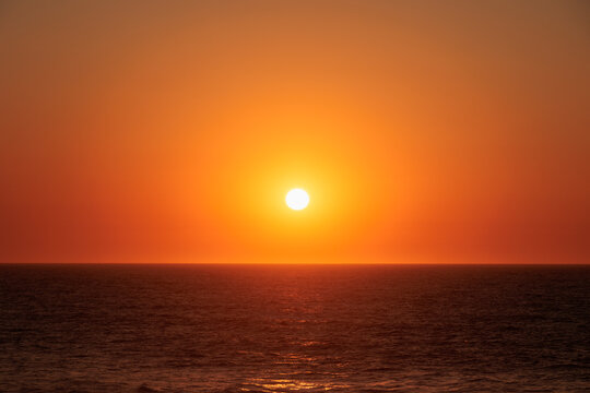 Bright sun setting above the Atlantic Ocean with clear orange sky, Portugal, Ovar – Furadouro, 9 October 2025 - Powered by Adobe