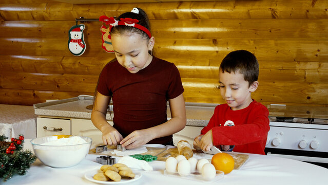The children are decorating Christmas cookies in the kitchen