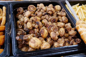 Fried champignon mushrooms. Various foods in outdoor fast food restaurant