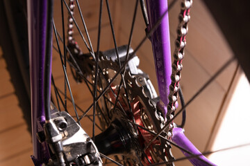 Close up of a bicycle rear drivetrain showing derailleur, cassette, and chain with red inner links. Selective focus.