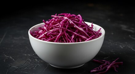 Obraz premium Vibrant red cabbage slaw in white bowl against dark textured backdrop