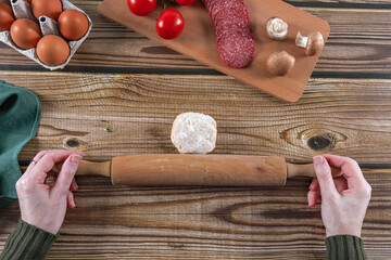 Step 5: The woman's hands prepare to roll out the dough on a wooden table.