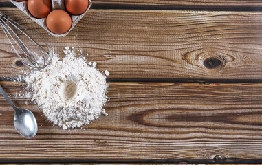 Step 1: Place flour, eggs and a whisk on a wooden table.