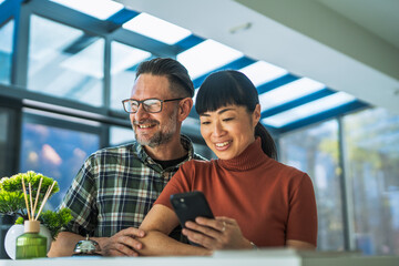 Interracial couple checking in hotel reception with smart phone