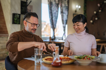 Mature multiracial couple enjoying lunch together at restaurant