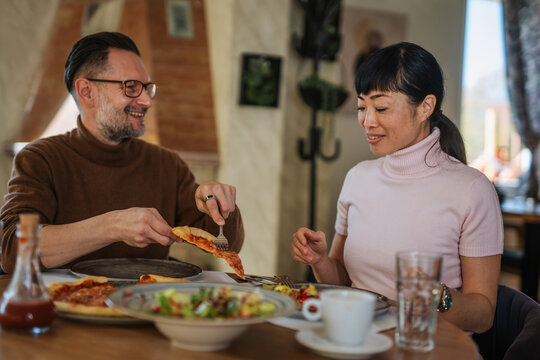 Happy couple enjoying pizza lunch at restaurant