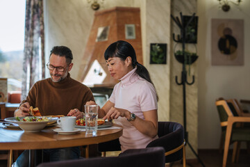 Mature diverse couple enjoying meal together in restaurant