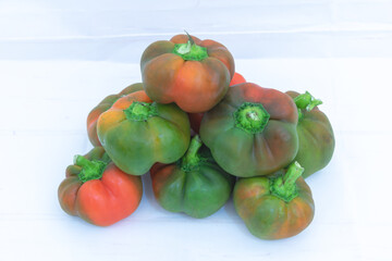 Pile of organic bell peppers in mixed green and red colors on white background