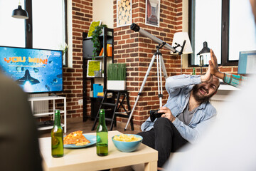 Friends gather in living room, celebrating game night with laughter, pizza and drinks. Caucasian and african american individuals sit on couch, giving high fives as television displays you win message