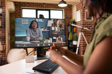 Cheerful black woman using digital device to manage team communication, happily discussing company...