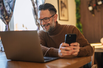 Mature man working remote using laptop and phone