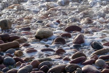 Obraz premium Foamy Waves Rolling Over Coastal Stones