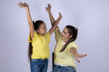 Mother and daughter are dancing with their arms raised