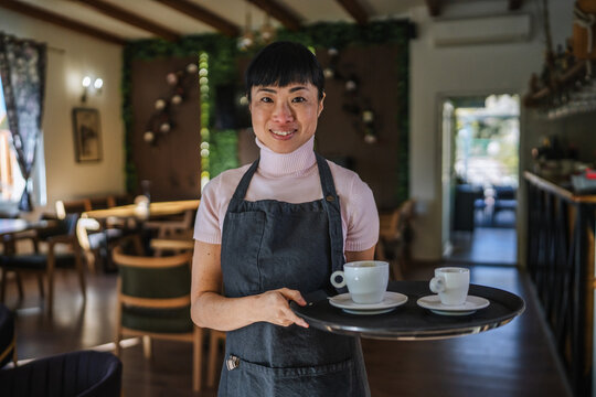 Waitress serving coffee to customers in restaurant