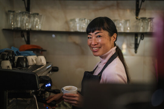Asian woman waitress working making coffee in cafe