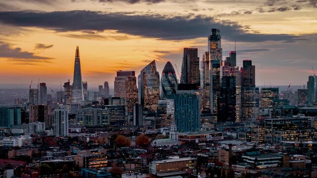 Aerial hyper lapse view of the illuminated, financial skyscrapers and the skyline at the City of London, England, during dusk