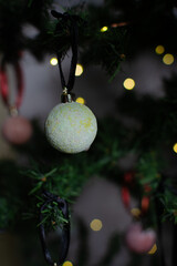 close up of Christmas ornaments on a green christmas tree, sparkly textured christmas tree baubles on artificial tree