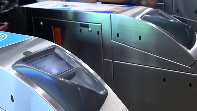 Passengers using contactless smart cards and electronic tickets to pass through an automatic turnstile gate at a modern public transportation station for convenient and fast city commuting