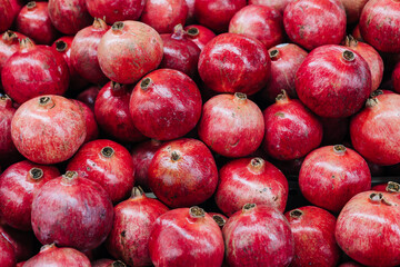 Fresh pomegranates stacked in a market during the harvest season showcasing vibrant red color and natural texture