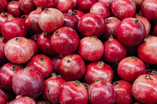 Fresh pomegranates stacked in a market during the harvest season showcasing vibrant red color and natural texture - Powered by Adobe