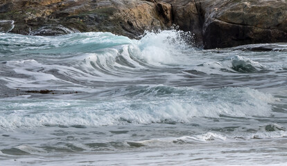 View across a breaking wave against a rocky coastline