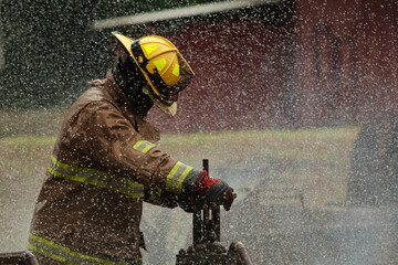 Fototapeta premium Firefighter closing gas valve during intense industrial fire incident.