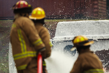 Firefighters spraying foam water to control extinguish an intense blaze.