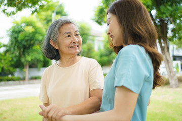 Obraz premium Caregiver assisting elderly Asian woman during a walk in the garden.