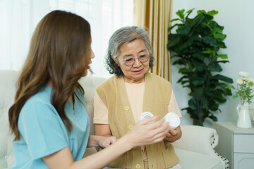 Caregiver helping elderly Asian woman organize and understand medications.