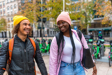 Diverse happy young friends walking together in city
