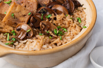 Overhead view vegan claypot rice with pan fried tofu, mushrooms and scallions, top view of crispy rice in a donabe on a marble countertop
